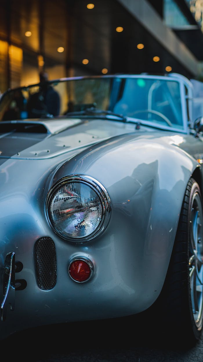 Close-up of a classic silver convertible car parked on a city street at night.